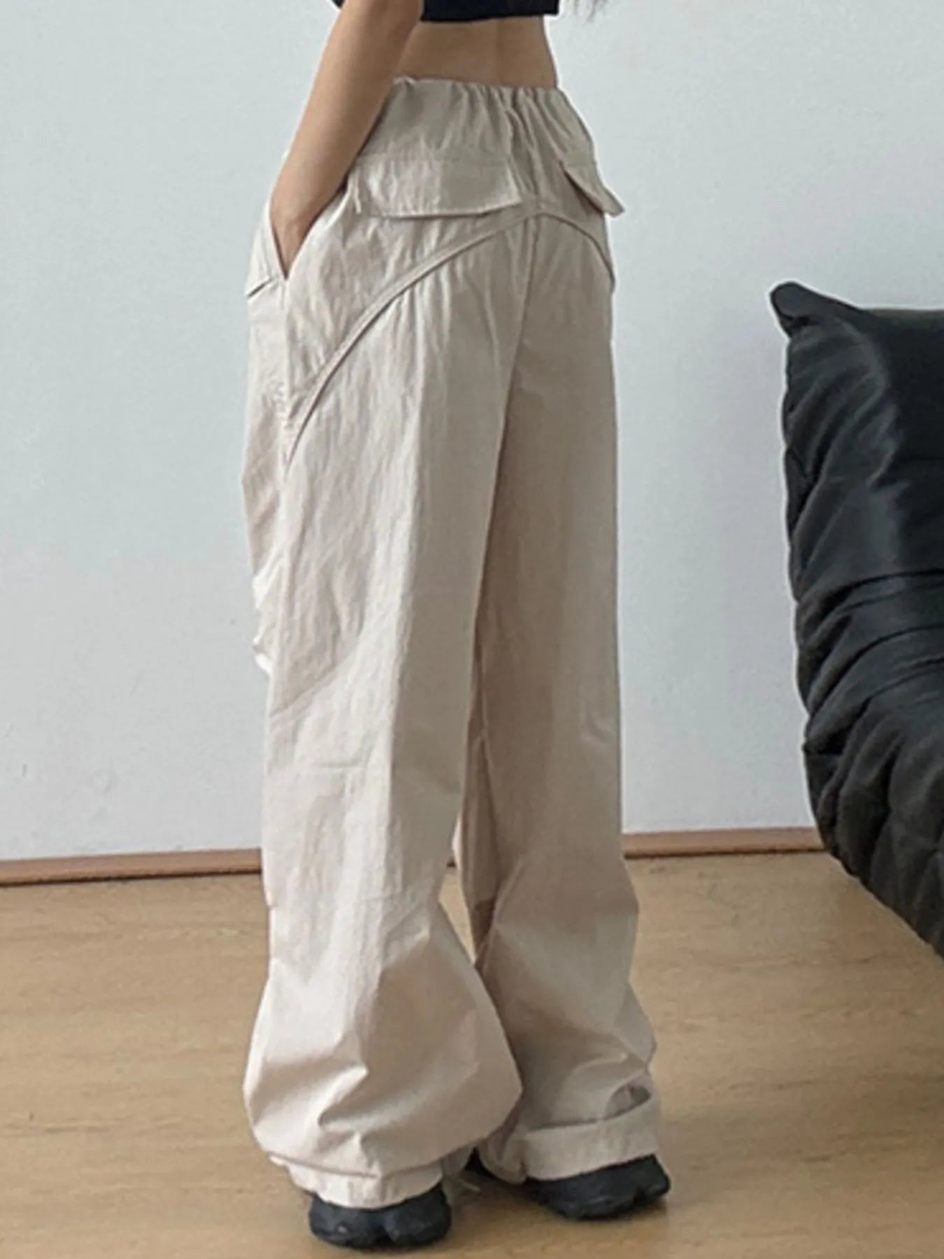 Beige wide-leg drawstring pants with draped pocket panel and relaxed straight legs