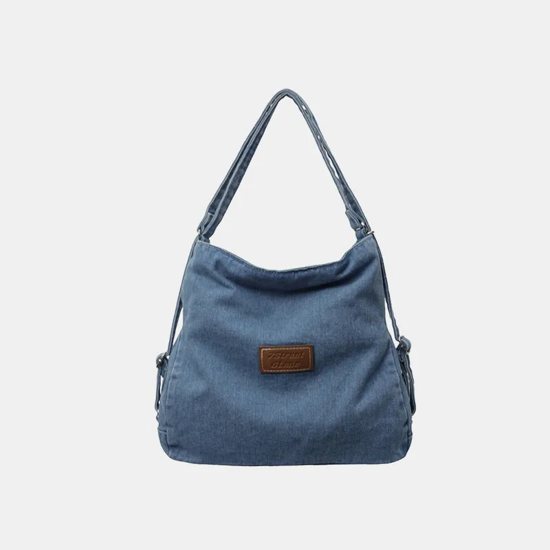 Adjustable strap denim shoulder bag in medium blue with front brown leather patch
