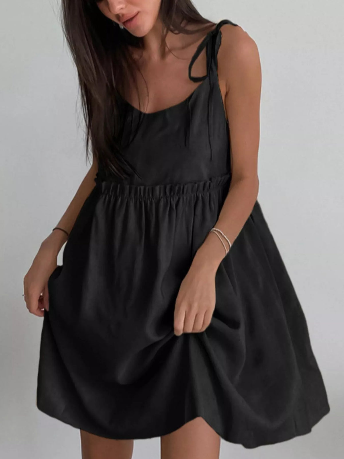 Black cotton mini dress with tie shoulder straps and gathered waist