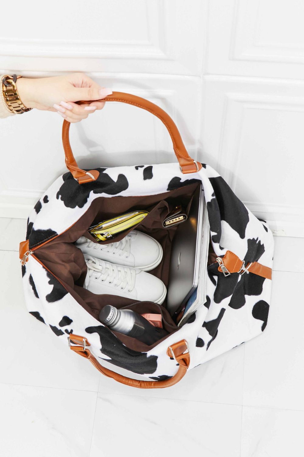 Open cow print plush weekender bag showing brown lining and interior pockets