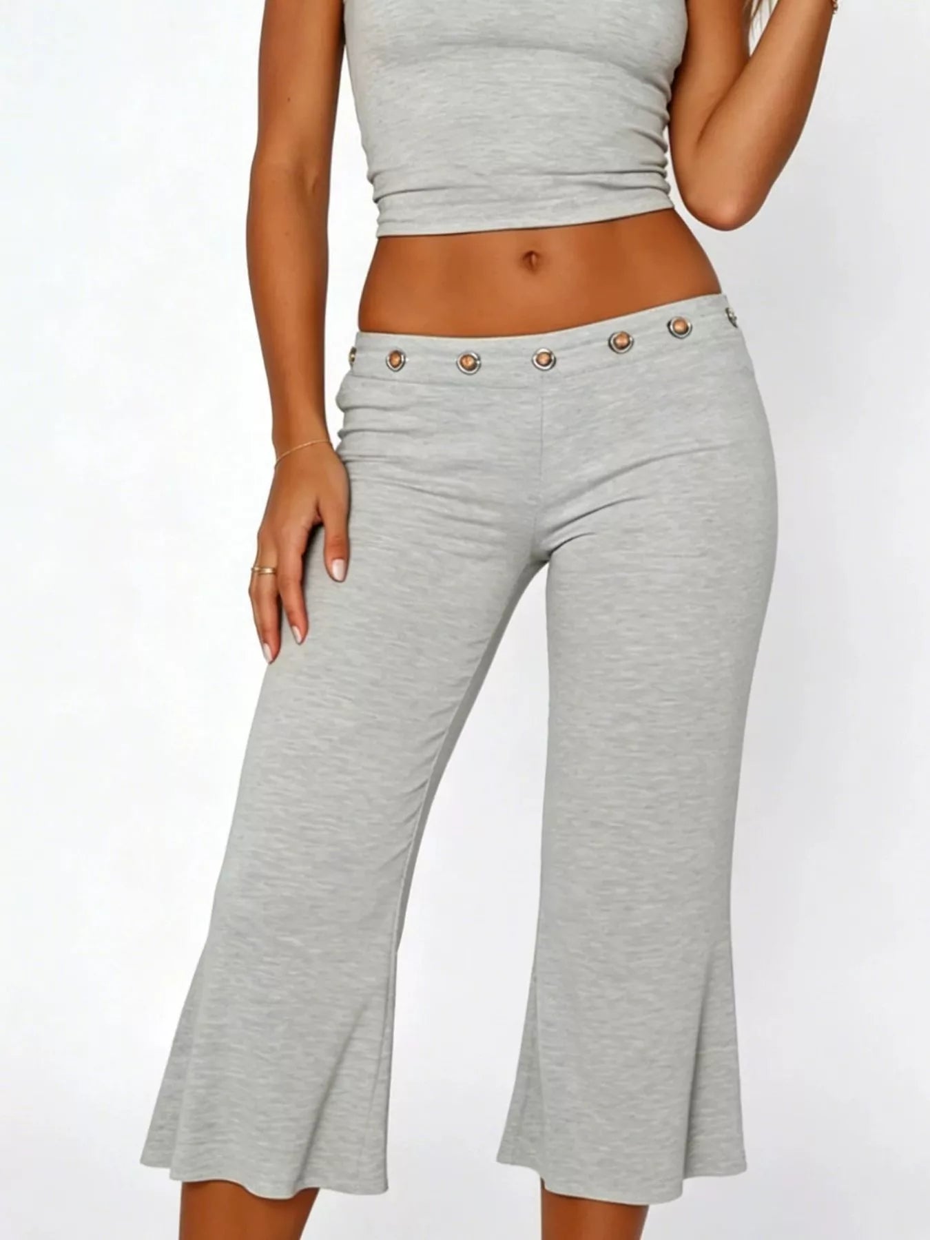 Mid-rise capri pants in heather gray with eyelet button waistband and flare at hem.