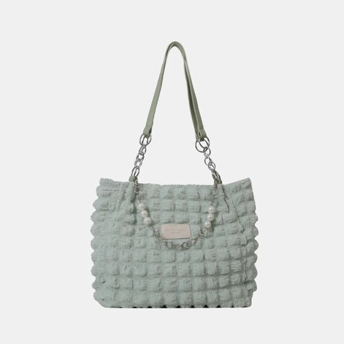 Light green bubble-textured tote bag with short straps and central pearl-stud charm
