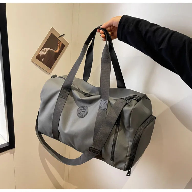 Dark gray large waterproof duffel bag with black handles, shoulder strap, and zip pockets