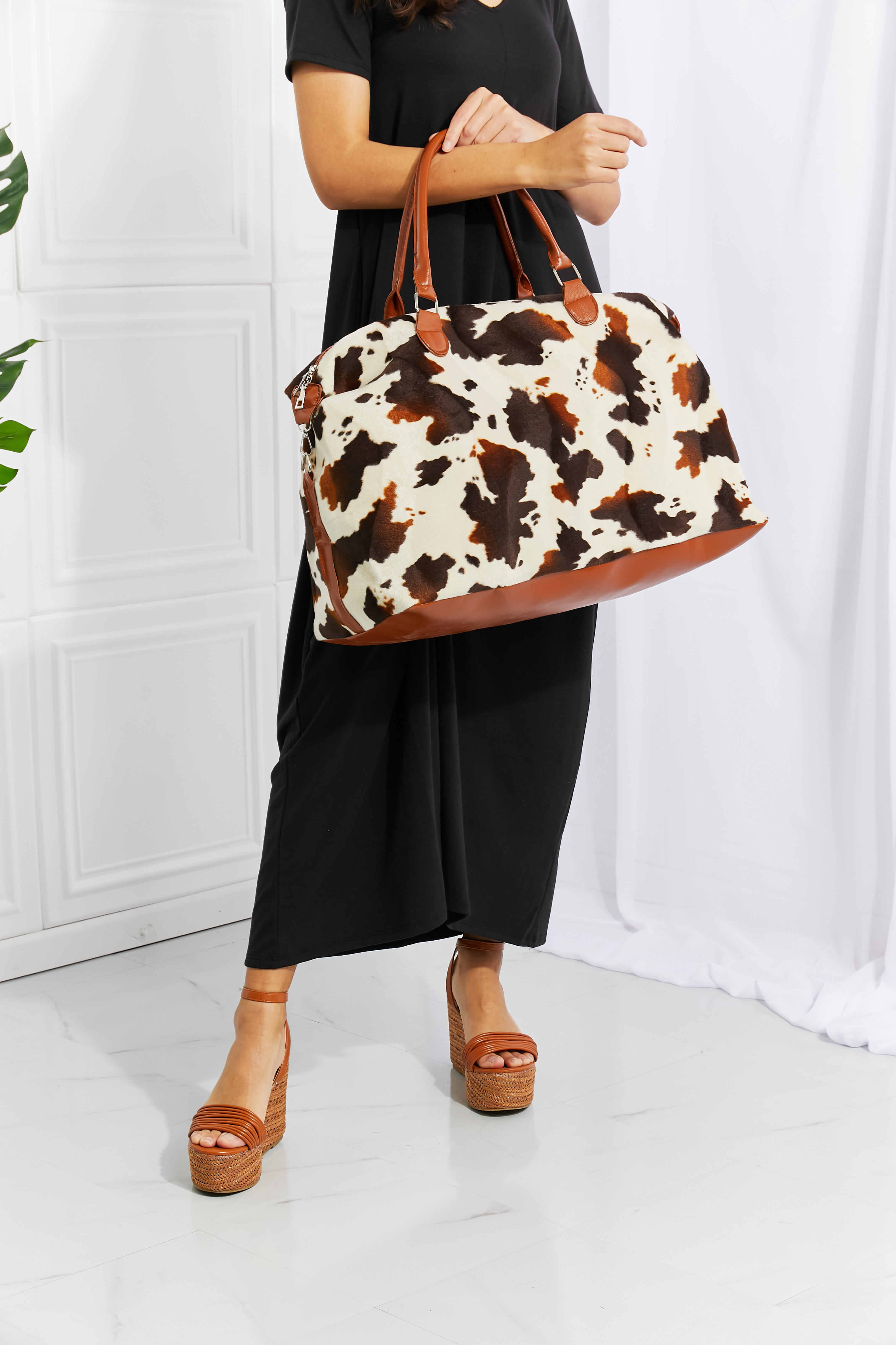 Animal print plush weekender bag with brown top handles and cow-spotted body