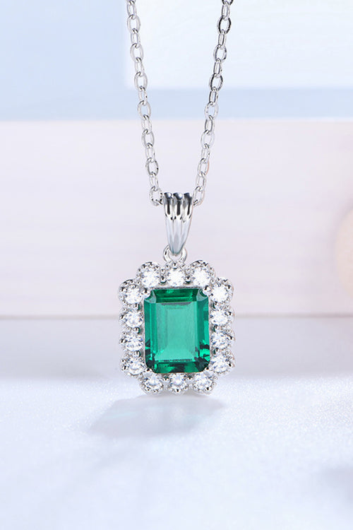 Emerald pendant necklace with square green center stone and round diamond halo, silver chain