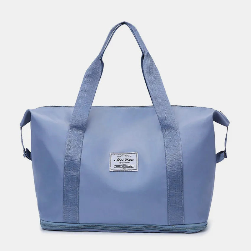 Dusty blue large duffle bag with long handles and front patch label