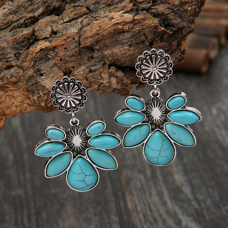 Turquoise flower earrings with dangling oval petals and silver-tone sunburst accents.