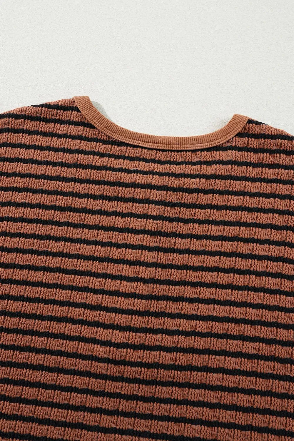 Caramel-and-black striped blouse fabric with ribbed crew neckline close-up