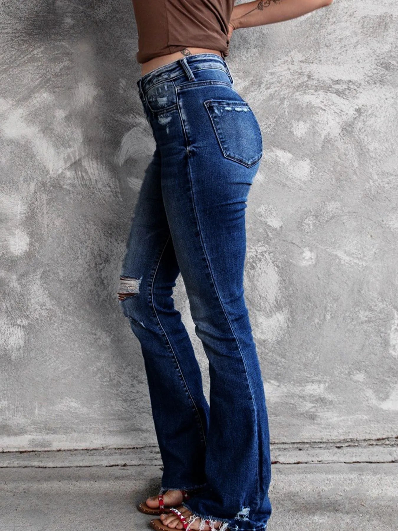 Medium blue distressed flare jeans with back pocket paneling and flared leg opening