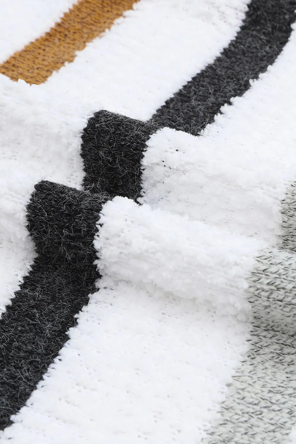 White knit sweater detail with dark and tan stripe bands on a fuzzy texture