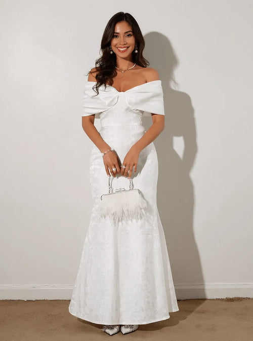 White off-shoulder maxi dress with waist bow, fitted bodice, textured fabric