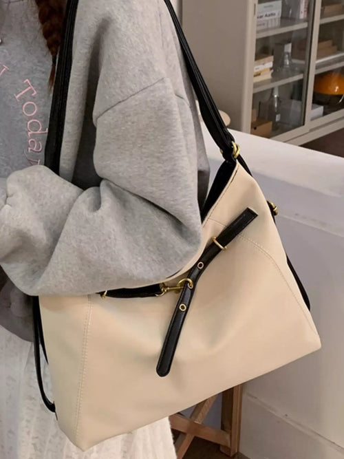 Ivory shoulder bag with black strap, side buckle details and gold-tone hardware