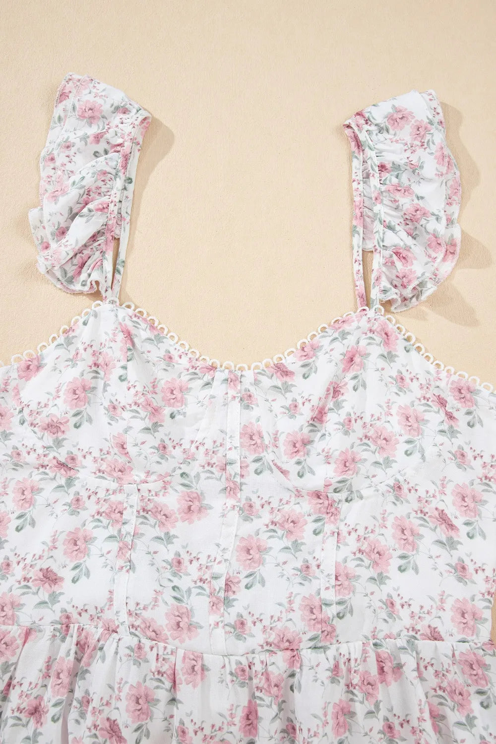 Floral peplum tank top detail view with blush pink blossoms and ruffle cap sleeves