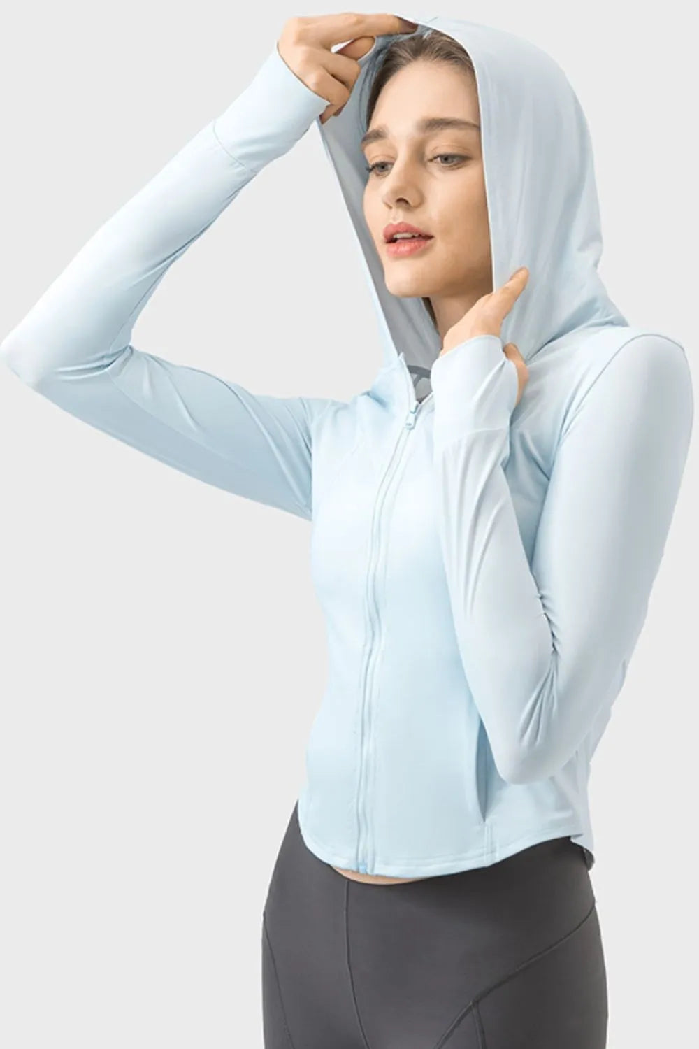 Light blue zip-up hooded jacket with kangaroo pocket, hood up and hands raised