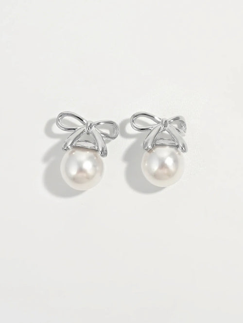 Silver bow stud earrings with round white pearls, matching pair.