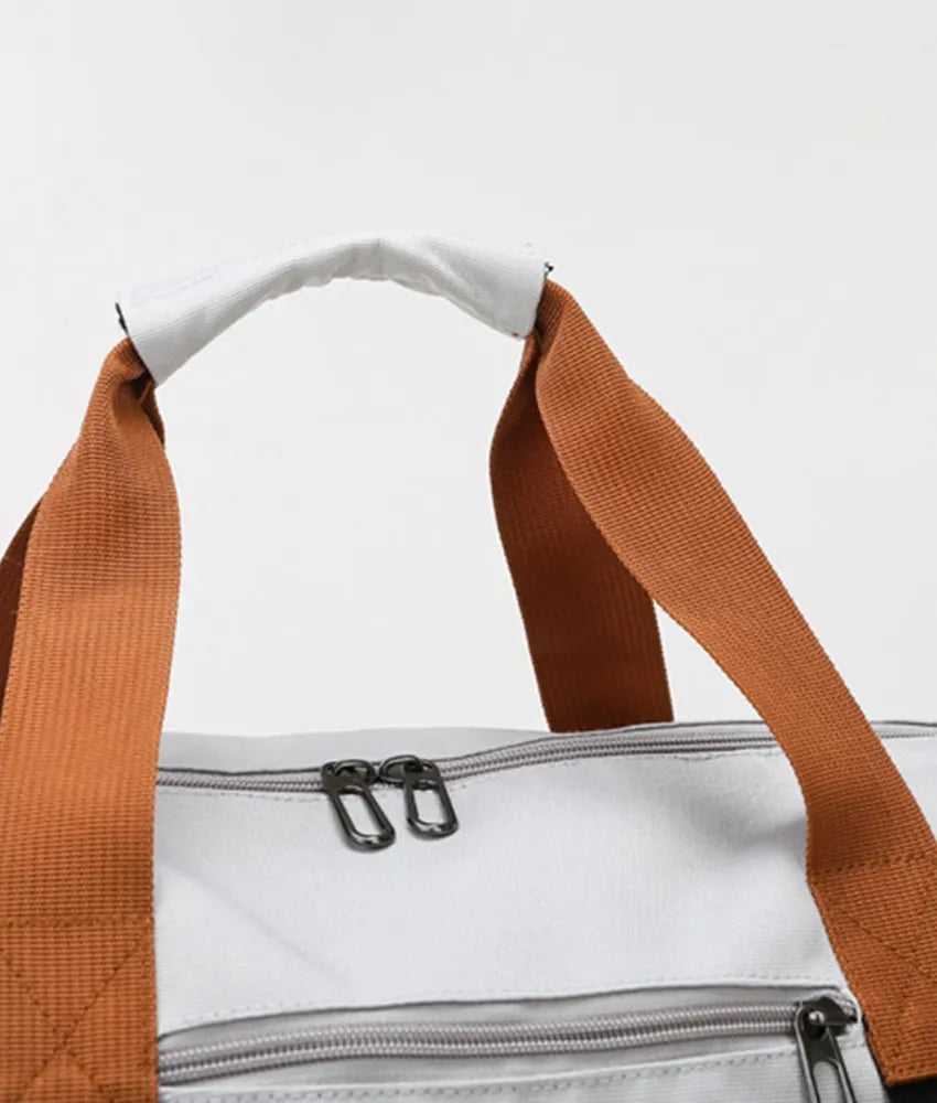 Oversize travel duffle bag top handles and zipper panel in light gray with brown webbing