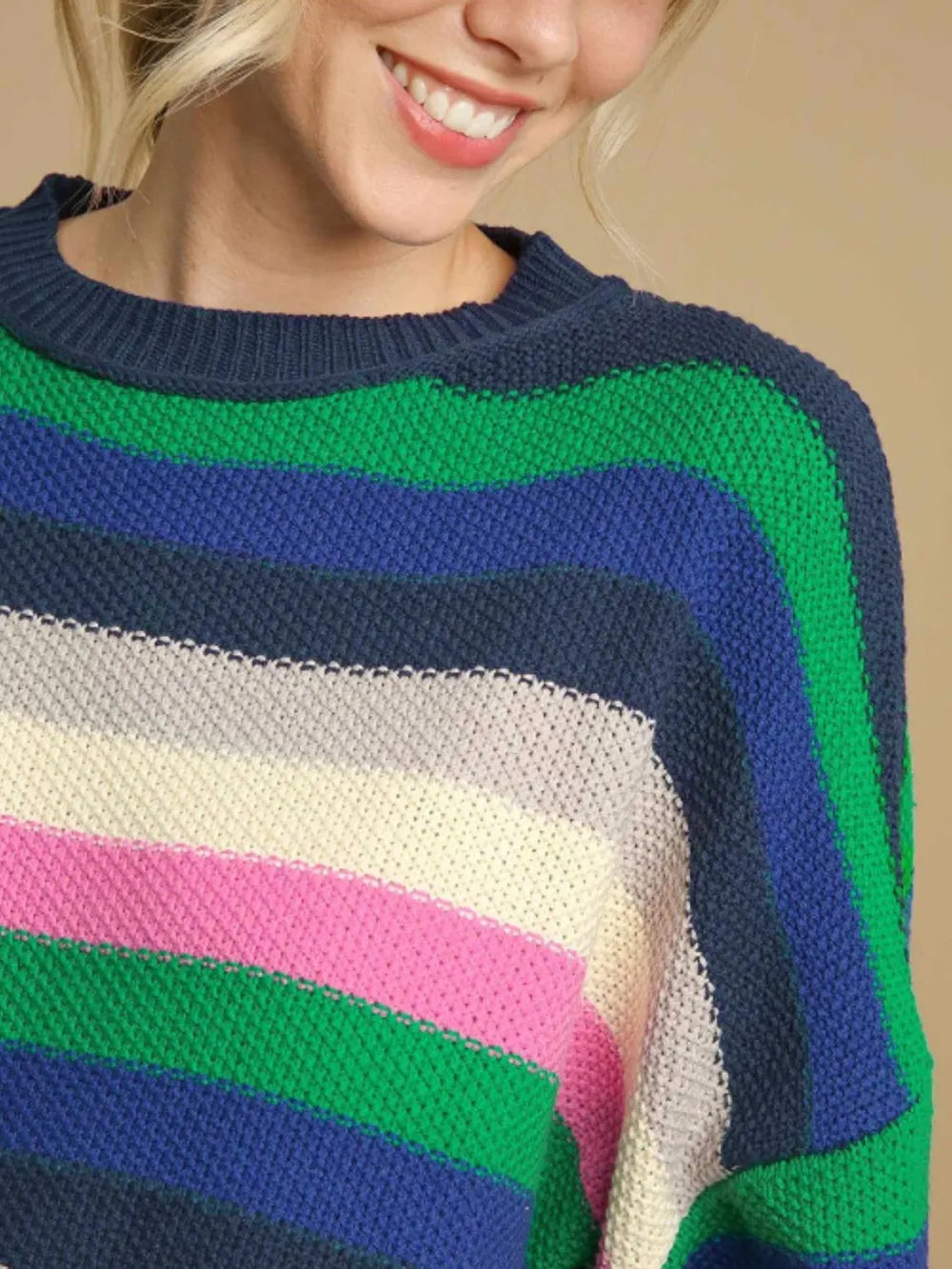 Striped knit sweater detail with navy collar, green and blue bands, white and pink stripes