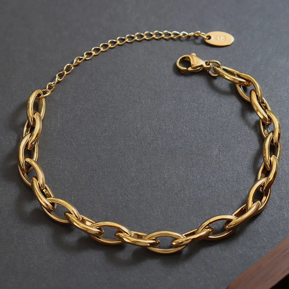 Gold chain bracelet with interlocking oval links and small tag clasp.
