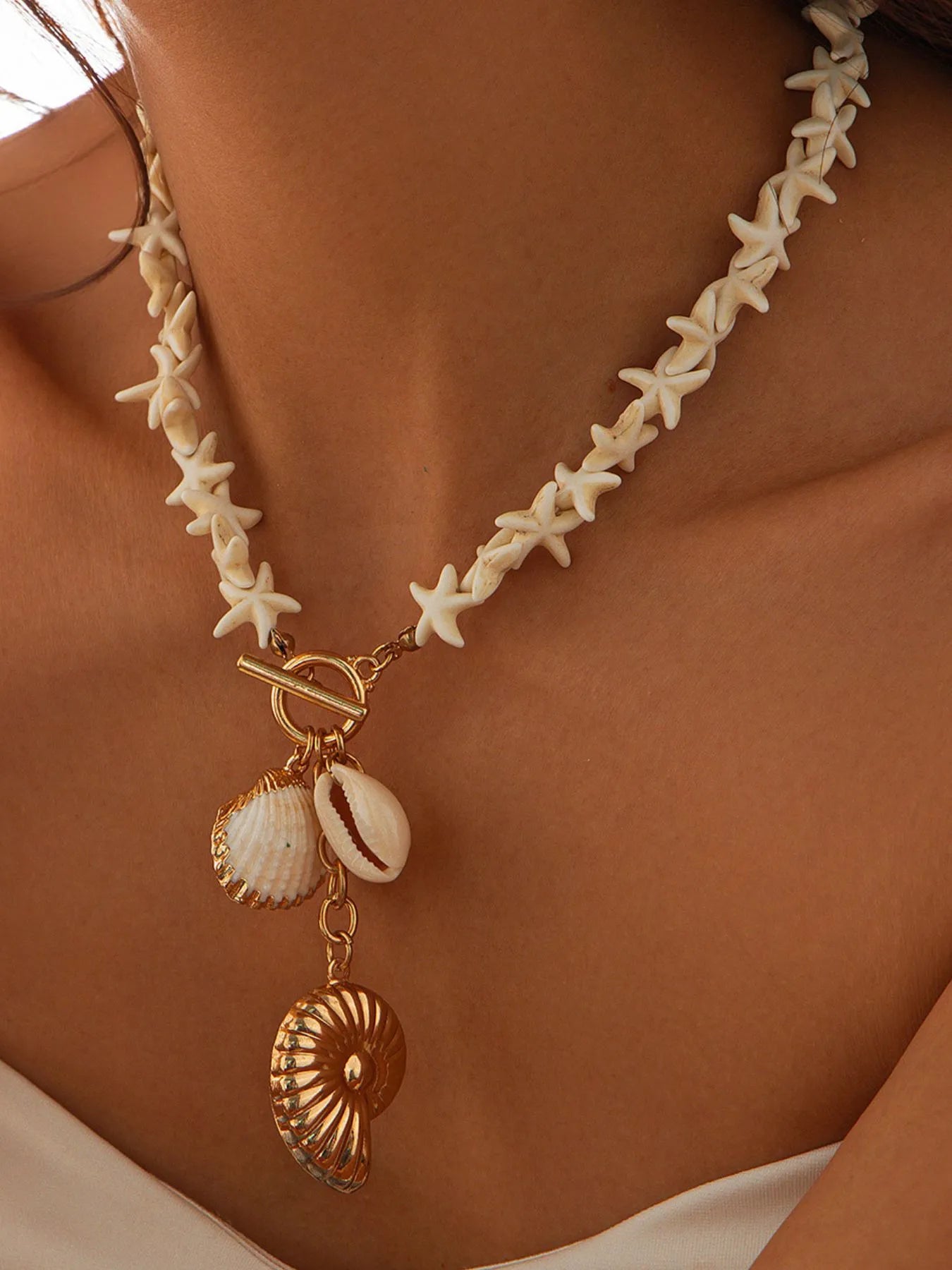 Gold shell pendant necklace with starfish-shaped links and two seashell charms on chain