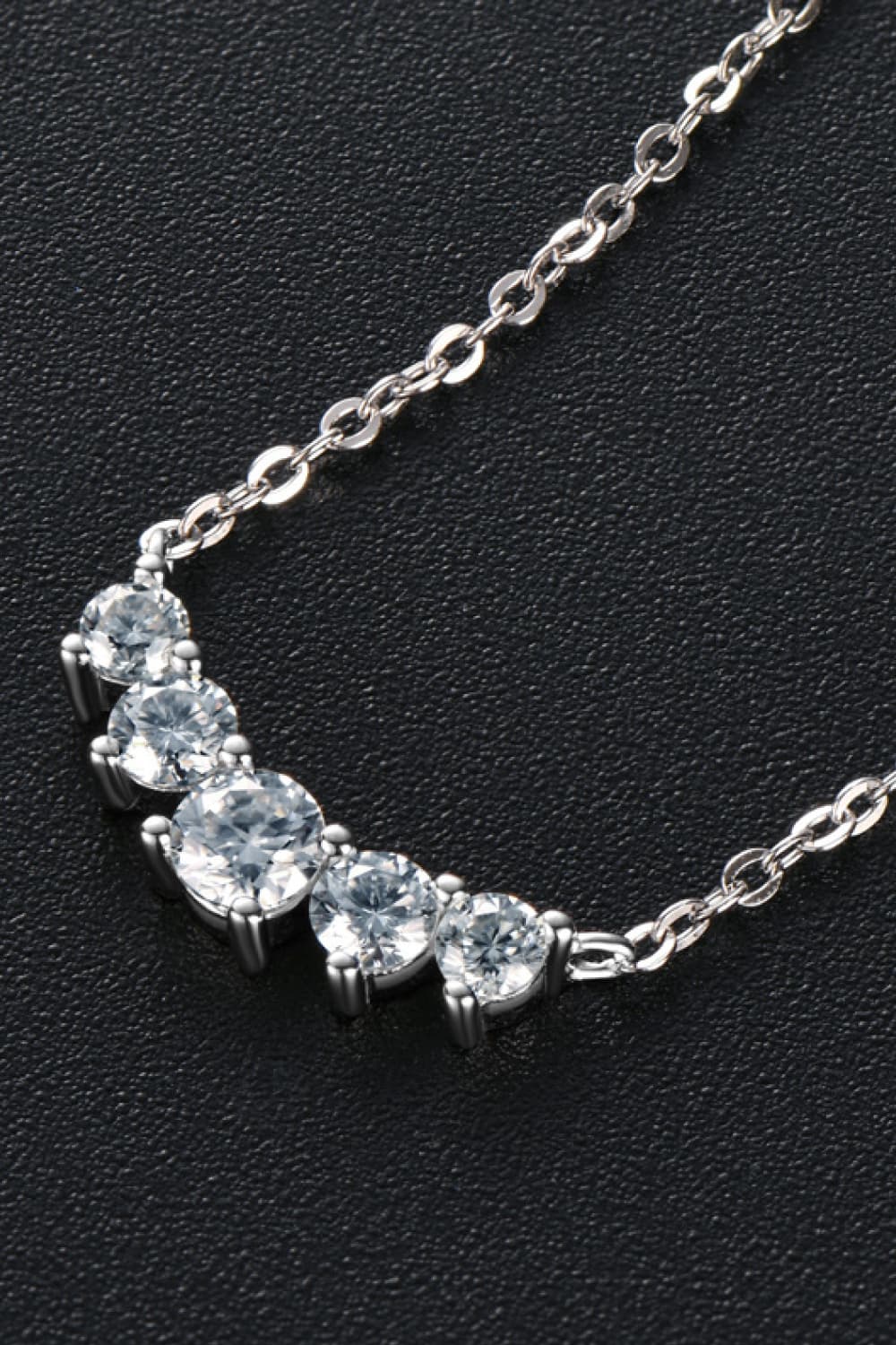 Silver pendant necklace with linked chain and clustered oval stones, close up