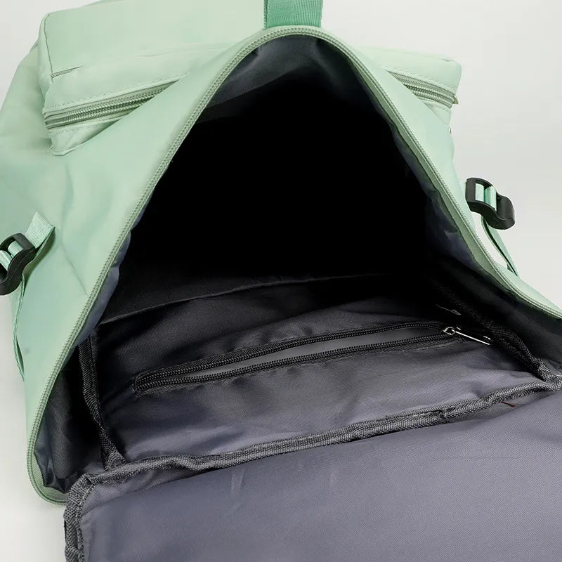 Mint green travel backpack interior with wide opening and front zip storage pocket.