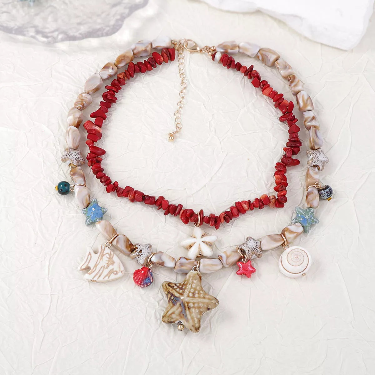 Multi-strand shell charm necklace with red beads and assorted seashell-style pendants