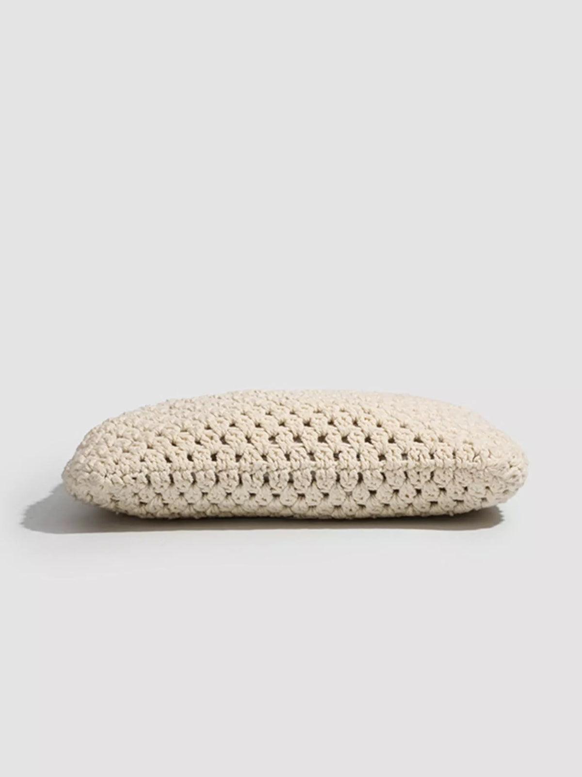 Textured cream crochet tote handbag with flat, rounded base and top opening.