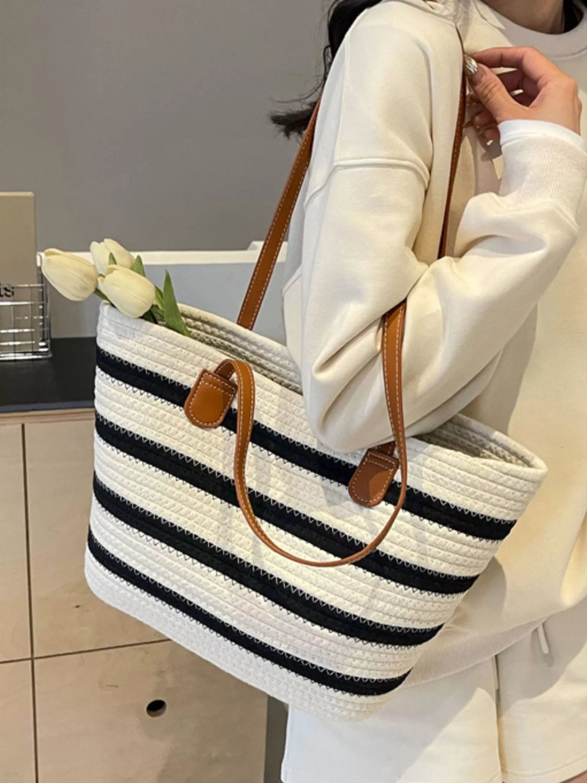 Striped straw tote bag with brown leather handles, white and navy horizontal stripes