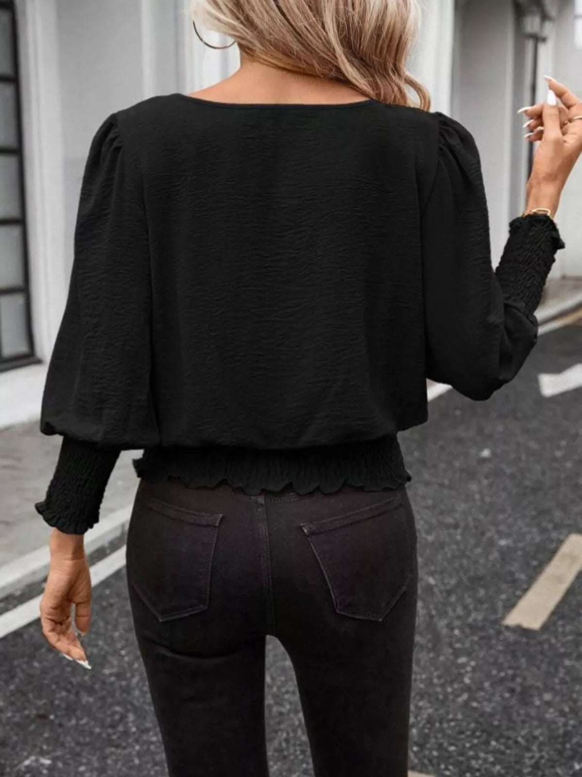 Black puff-sleeve smocked polyester blouse, back view with elastic cuffs and hem