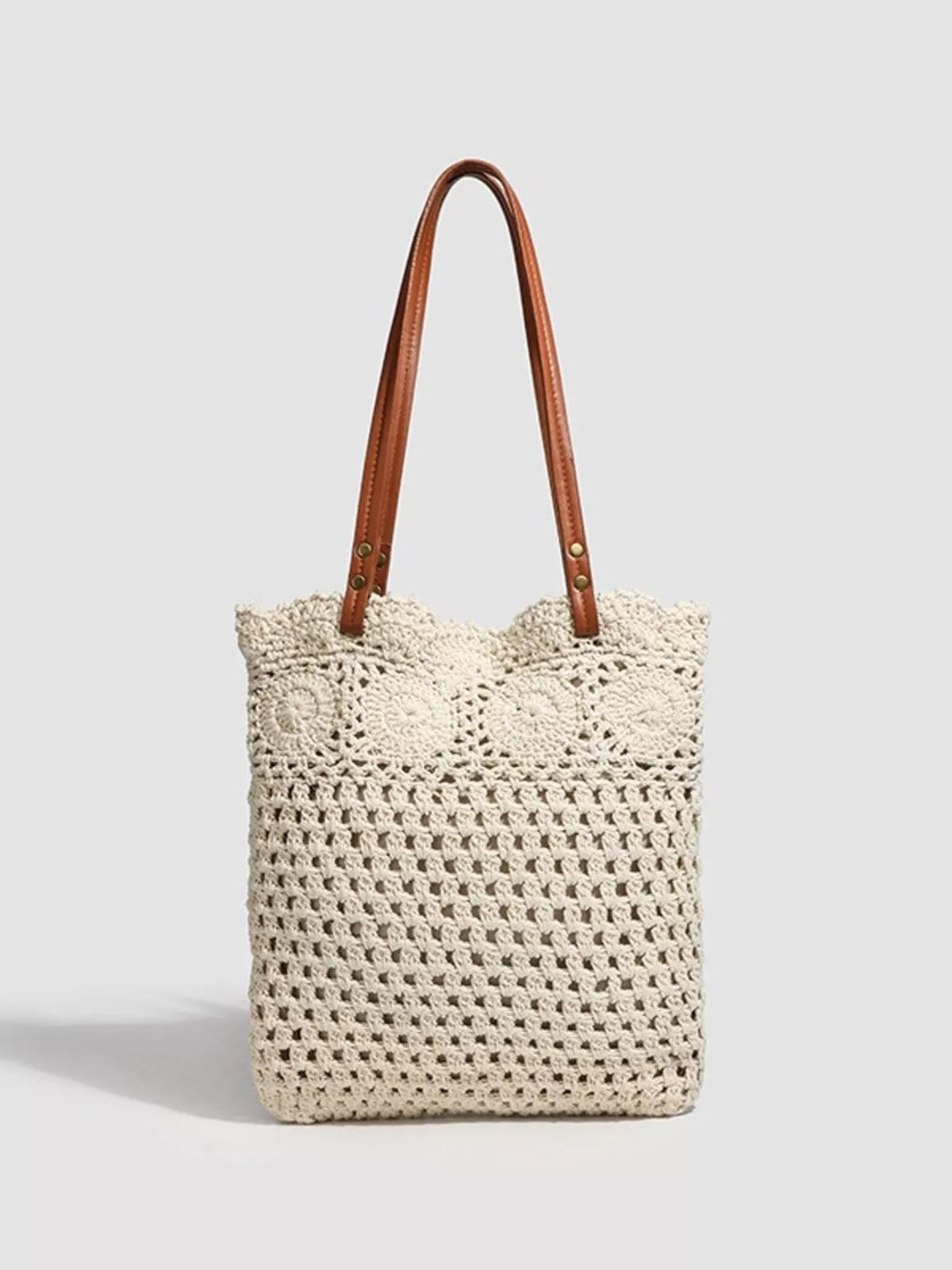 Crochet knit tote handbag with top handles, cream body and brown leather straps.