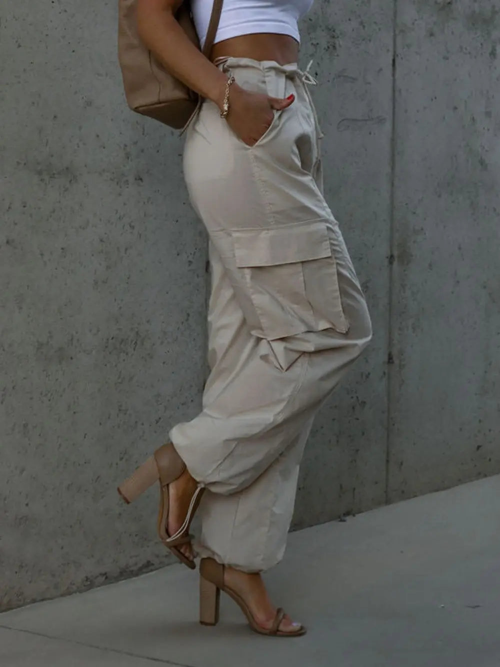 Beige cargo-style drawstring pants with flap pockets and ankle cuffs