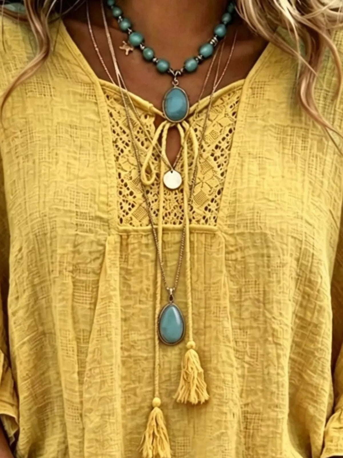 Yellow tie-neck blouse with lace panel and tassel accents at the neckline