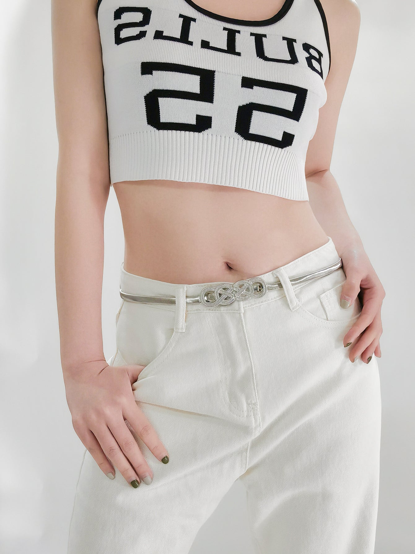 Gold-tone metal knot buckle belt on light pants, worn at the waist