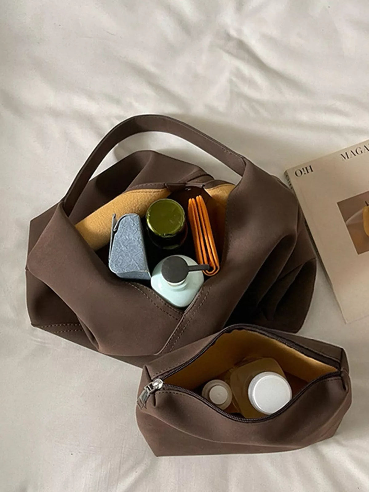 Brown slouchy suede shoulder bag open with small items inside
