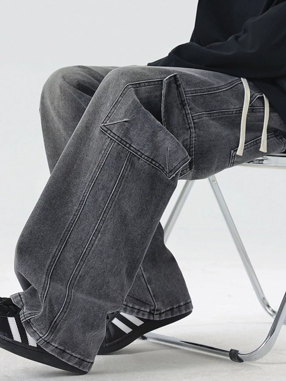 Washed dark gray wide-leg cargo jeans with patch pockets and long drawcord waist ties