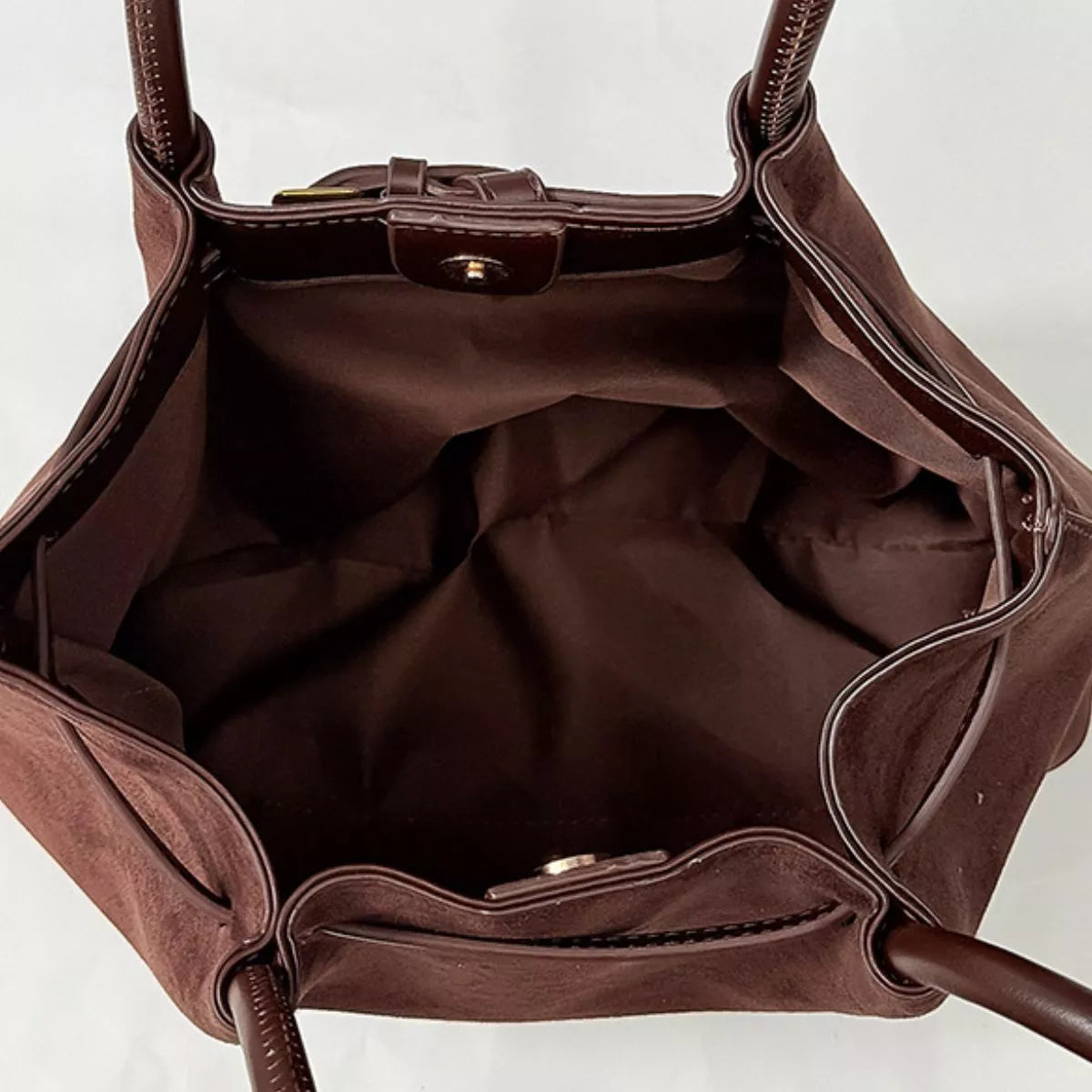Interior view of dark brown suede shoulder bag with lining and front zip pocket
