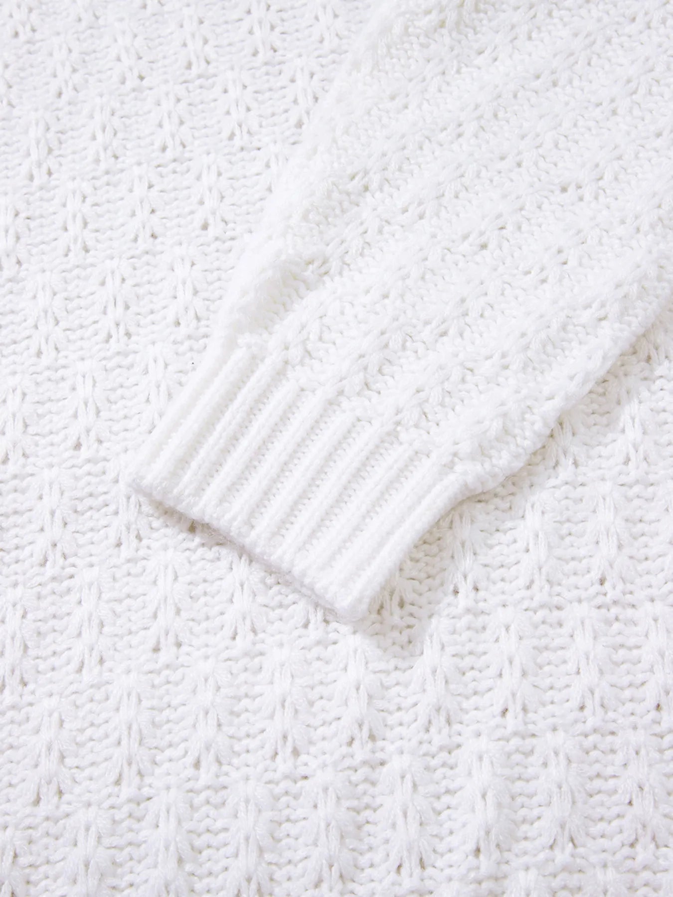 White textured knit sweater sleeve close-up with ribbed cuff detail.