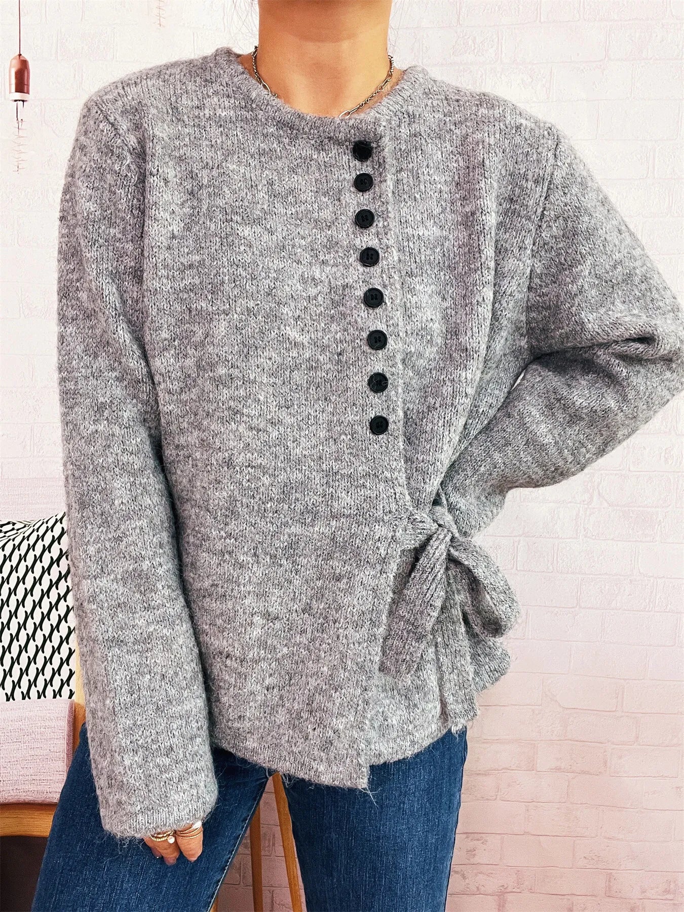 Gray button-front side-tie sweater with long sleeves and black buttons down center