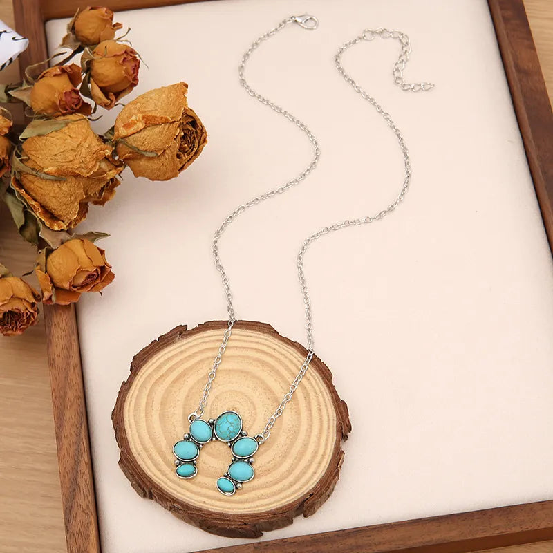 Turquoise pendant necklace with oval stone cluster on silver-tone chain.