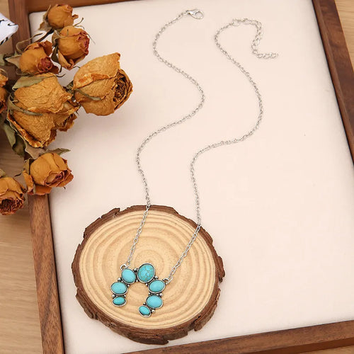 Turquoise pendant necklace with oval stone cluster on silver-tone chain.