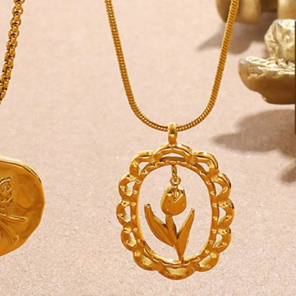 Gold-tone chain necklace with large circular floral pendant and hanging bud