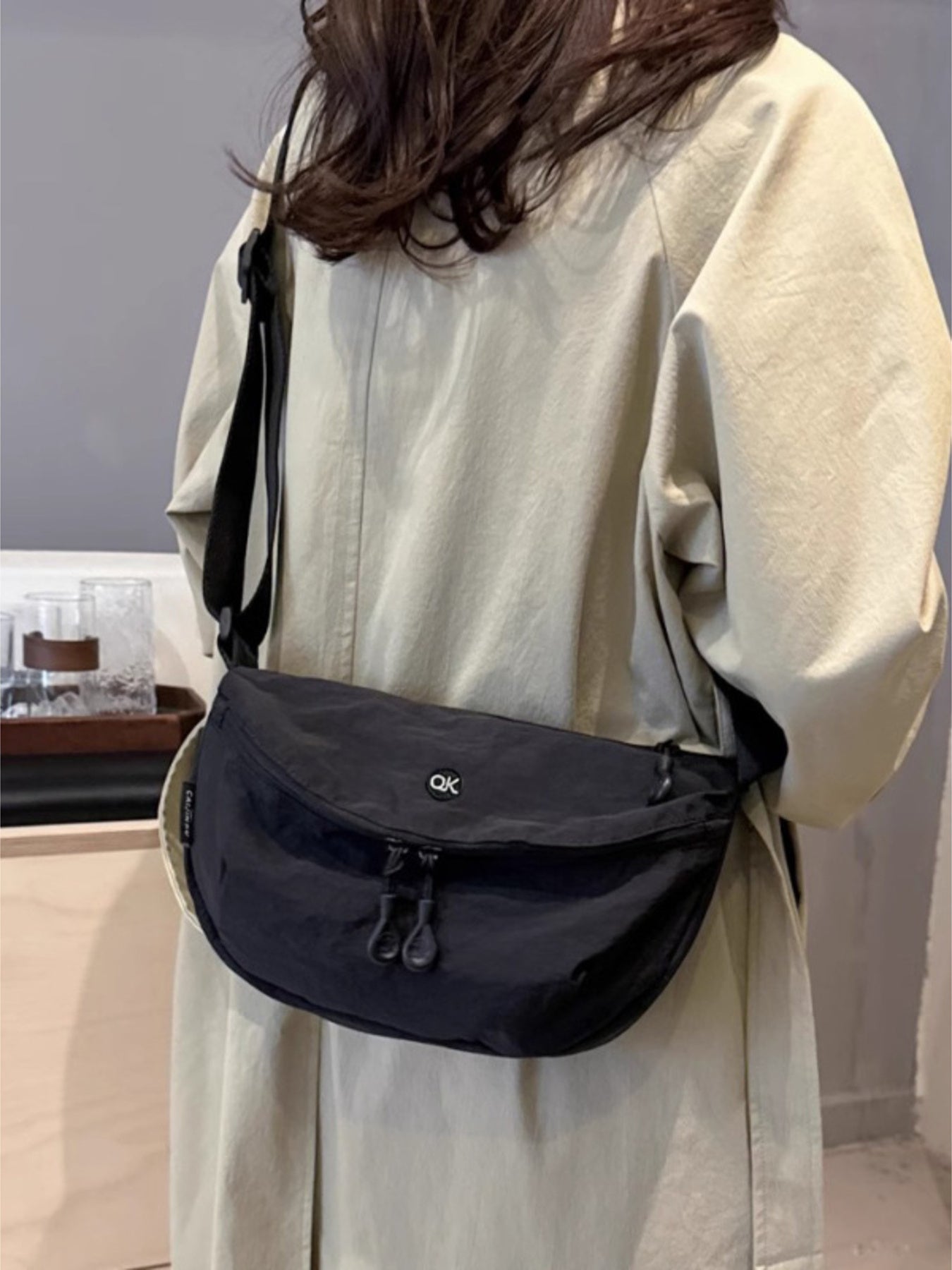 Lightweight nylon crossbody bag in black with adjustable strap, medium size, featuring a small OK logo.