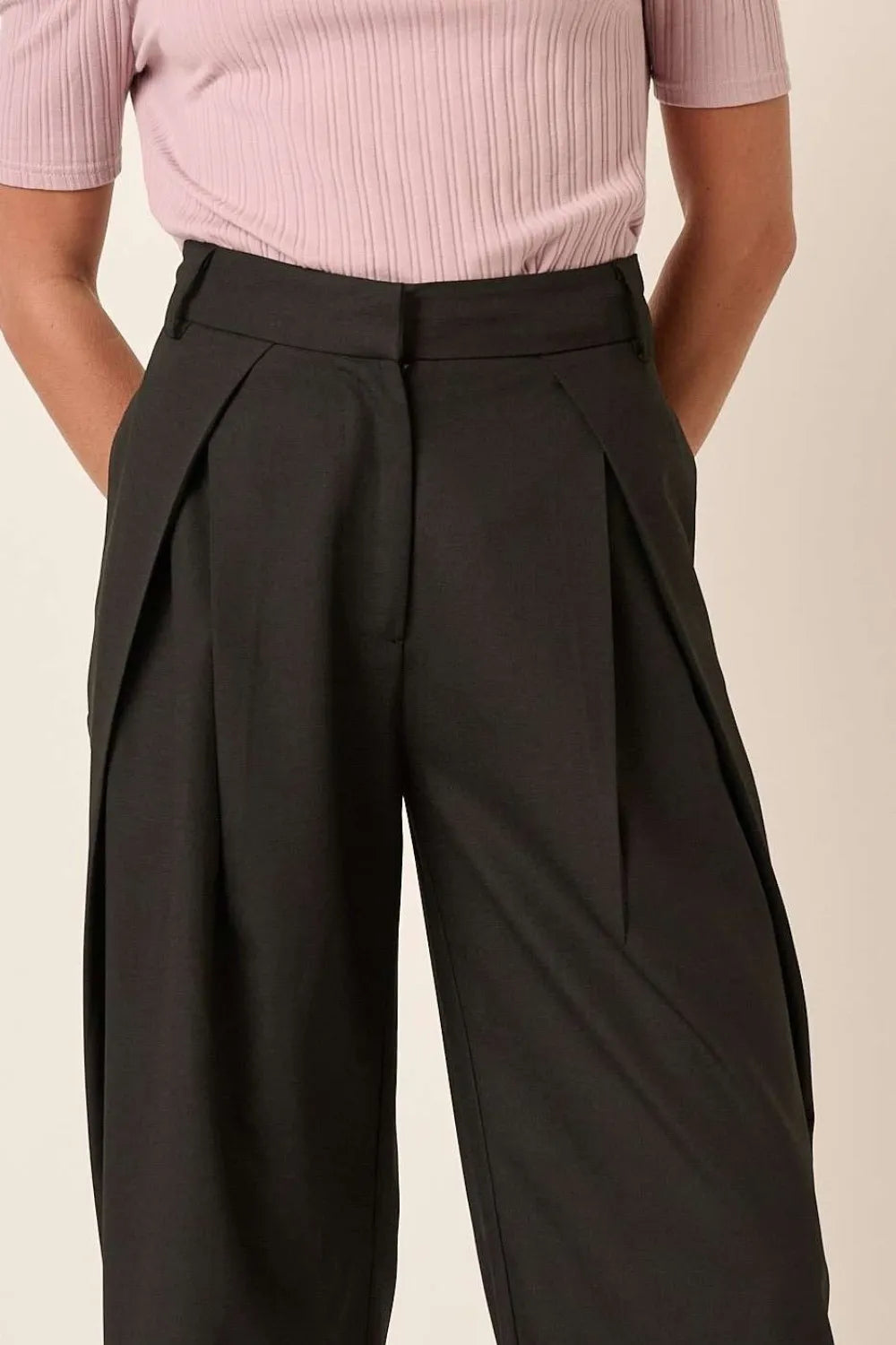 Black high-waisted wide-leg pants with deep pleats and angled front drape