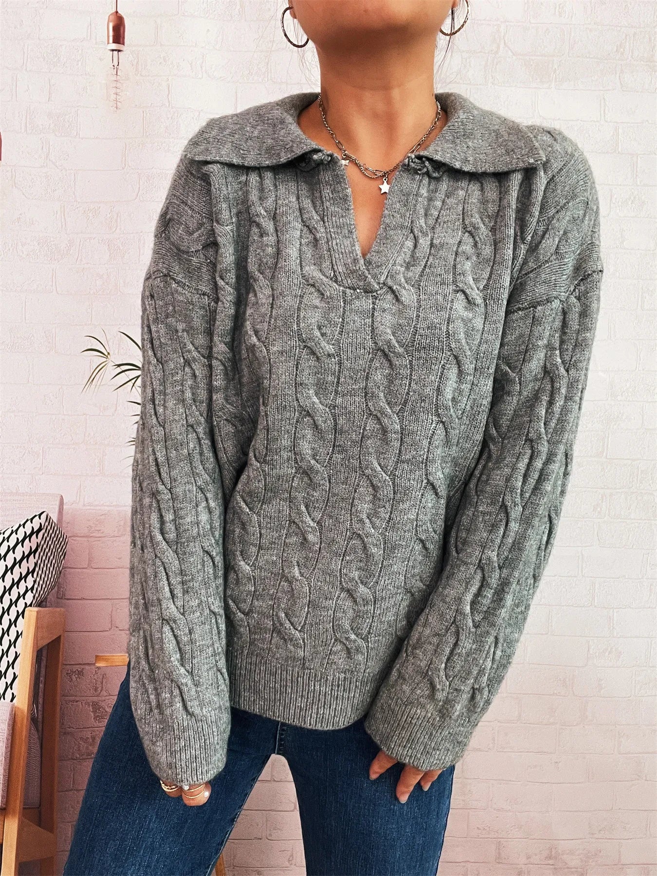 Gray cable-knit johnny-collar sweater with long sleeves, cable texture and V neckline.