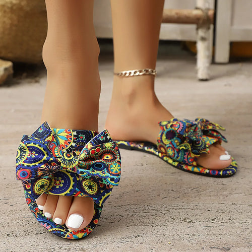 Colorful paisley open-toe flat sandals with large bow at front and silver chain ankle strap