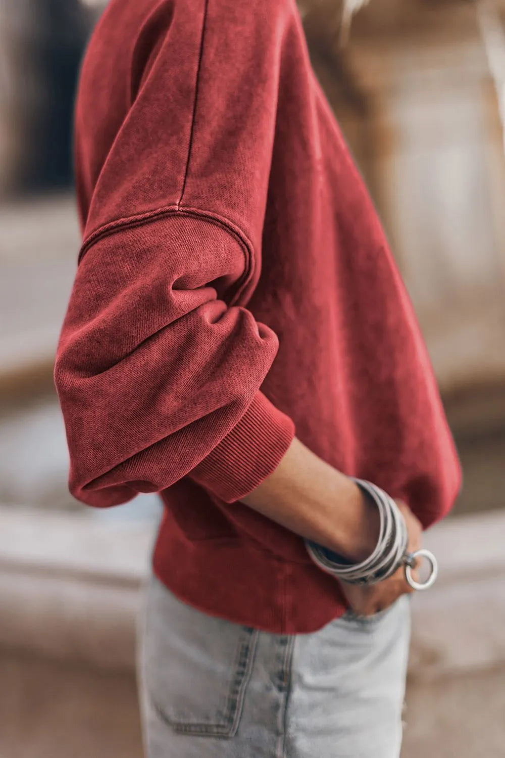 Deep red sweatshirt sleeve detail with ribbed cuff and cuffed hemline