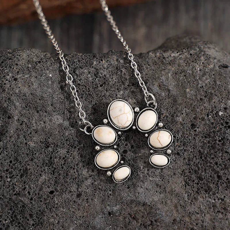 White oval stone pendant necklace on silver-tone chain, circular clustered design.