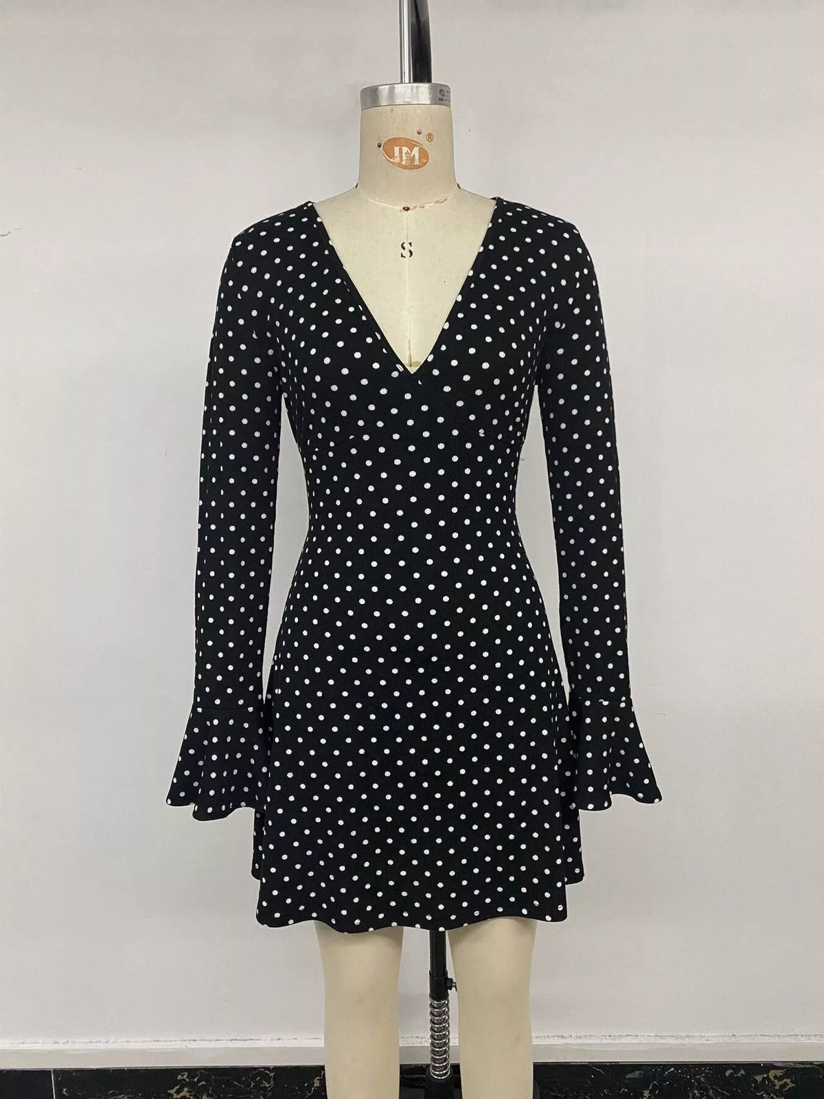 Black polka dot long sleeve mini dress with V-neck and ruffle hem