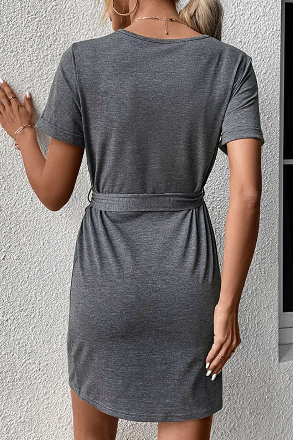 Dark gray tee dress with tie waist and short cuffed sleeves, back view