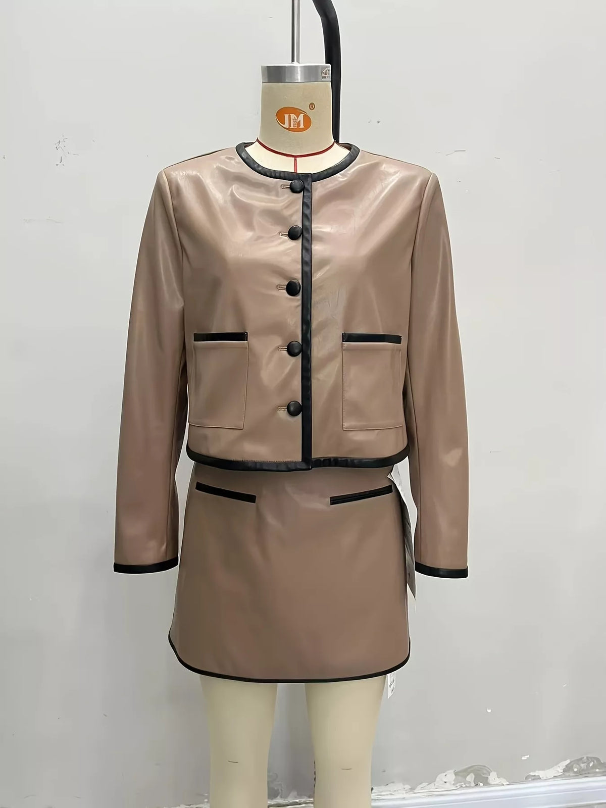 Tan jacket and mini skirt set with black trim, button front, and pocket details